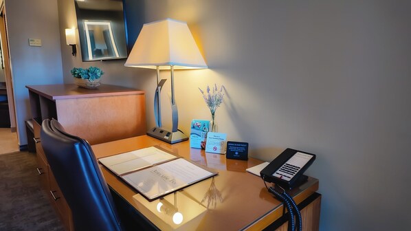 A hotel reception desk with a lamp, a phone, a notepad, a welcome brochure, and a non-smoking sign.