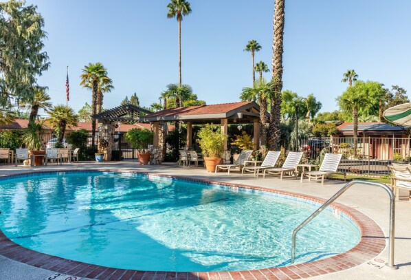 A swimming pool with lounge chairs and a covered seating area.