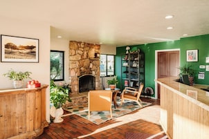 Um interior aconchegante com lareira de pedra, balcão de madeira e parede verde decorativa.