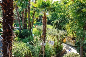 Um jardim exuberante com palmeiras, uma placa indicando o Adelaide Motel Inn e uma cerca de madeira.