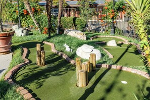 Un jardín ajardinado con un sendero serpenteante, postes de madera y una escultura de conejo blanco.