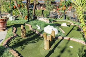 Un jardín ajardinado con un sendero serpenteante, postes de madera y una escultura de conejo blanco.