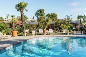 Piscina com espreguiçadeiras e um pergolado.