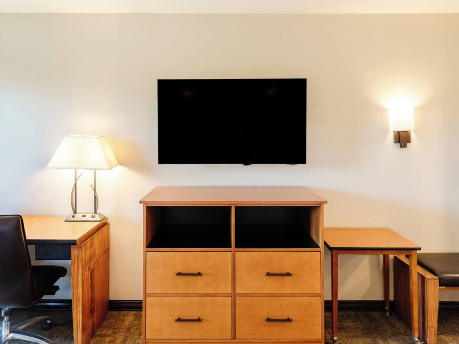 Ein Hotelzimmer mit Schreibtisch, Stuhl, Fernseher und Lampe.