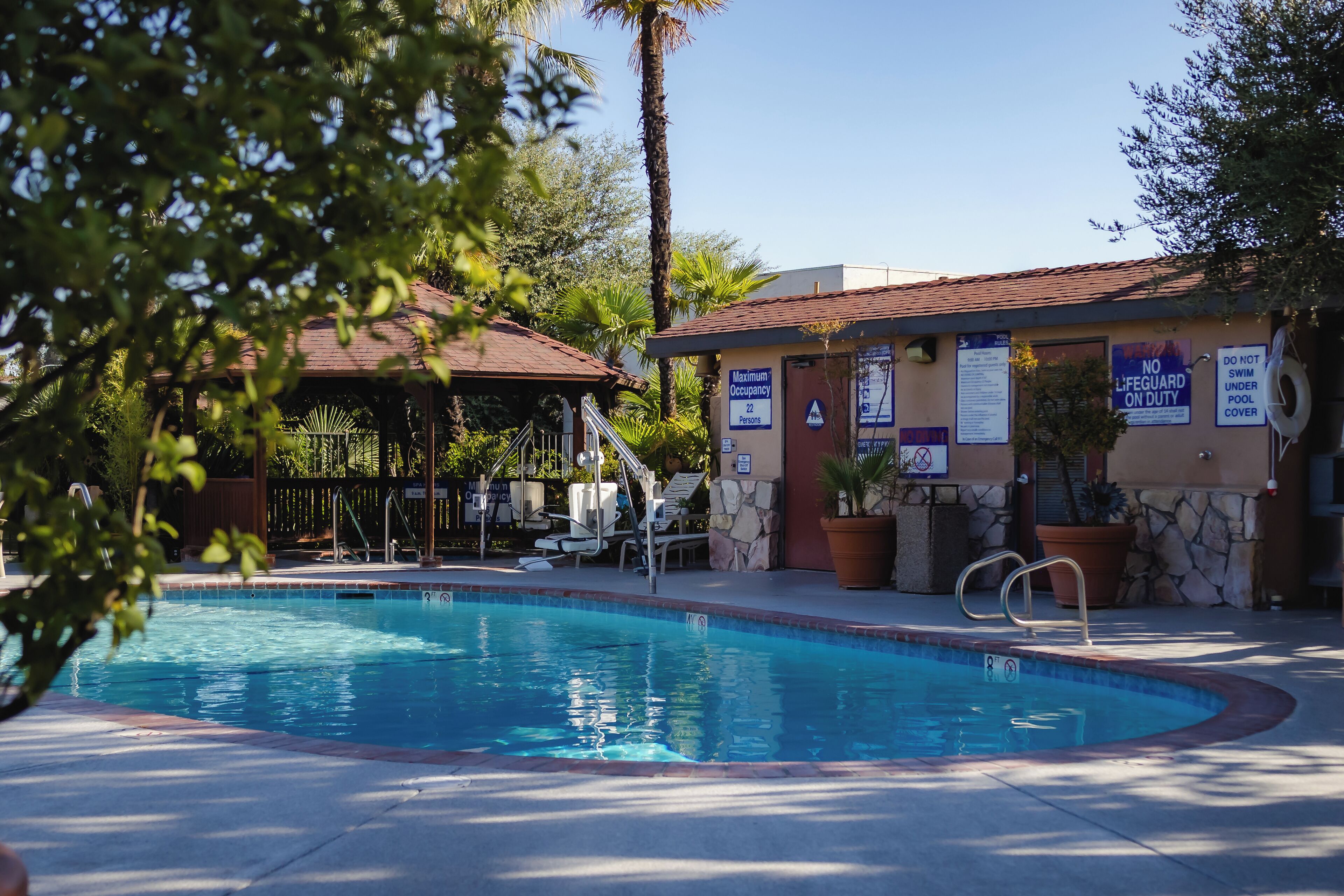 A swimming pool with a lifeguard station, lounge chairs, and a covered area with a roof.