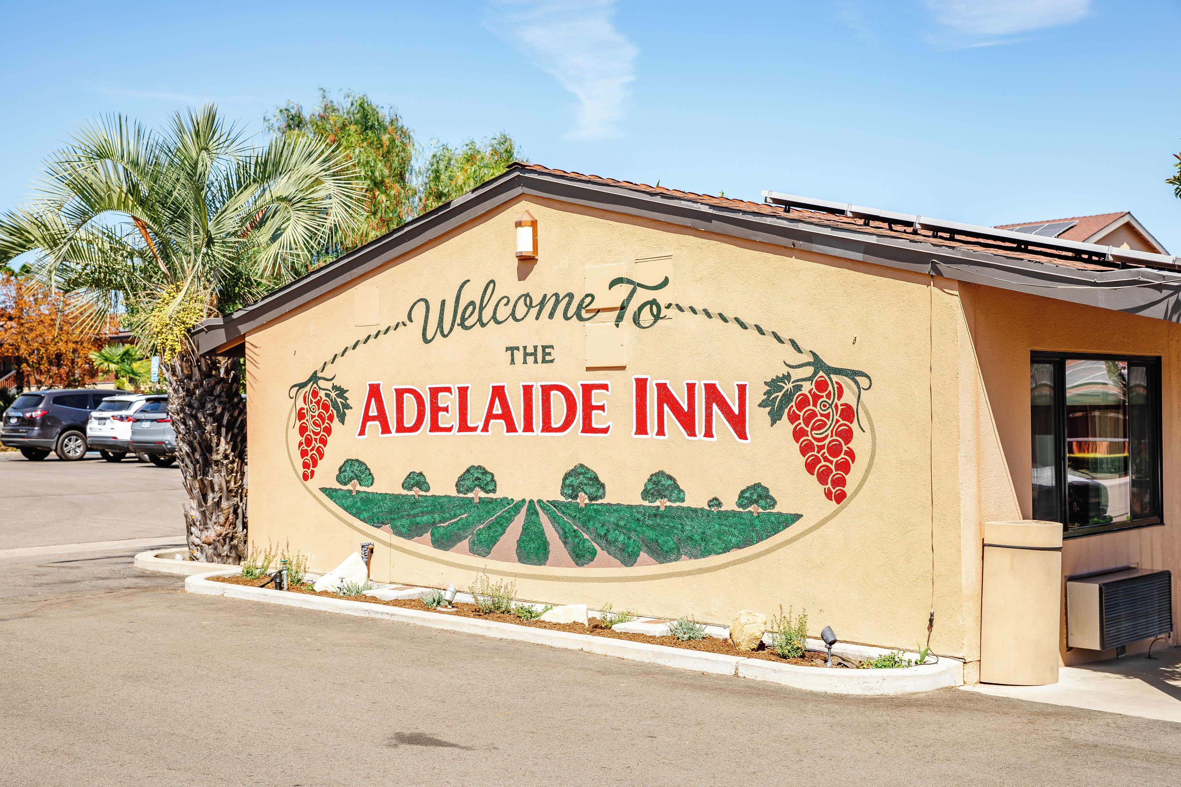 Een gebouw met een bord waarop staat 'Welcome to The Adelaide Inn', met afbeeldingen van druiven.