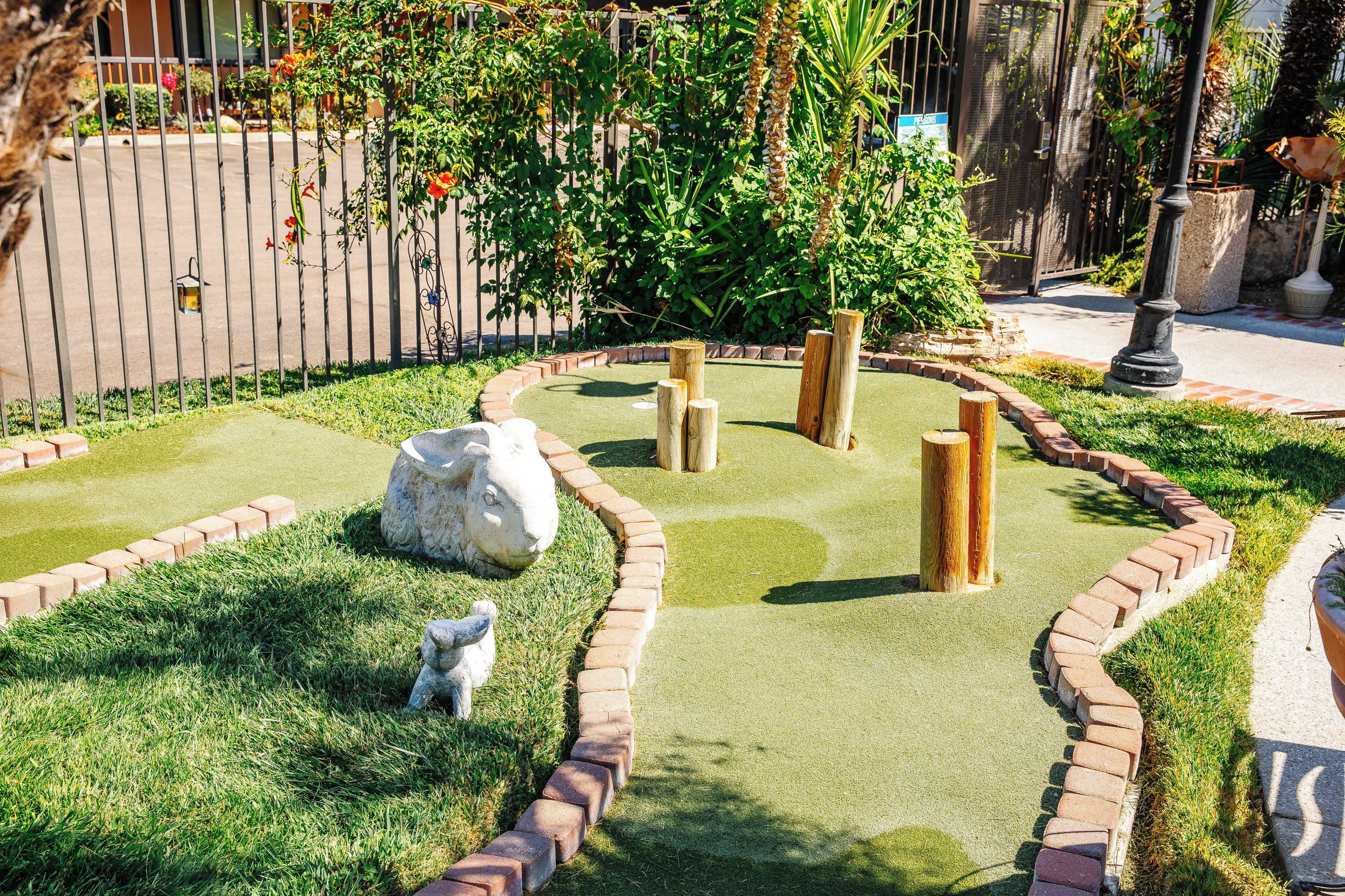 A landscaped garden with a stone statue, a small pond, and a brick border.