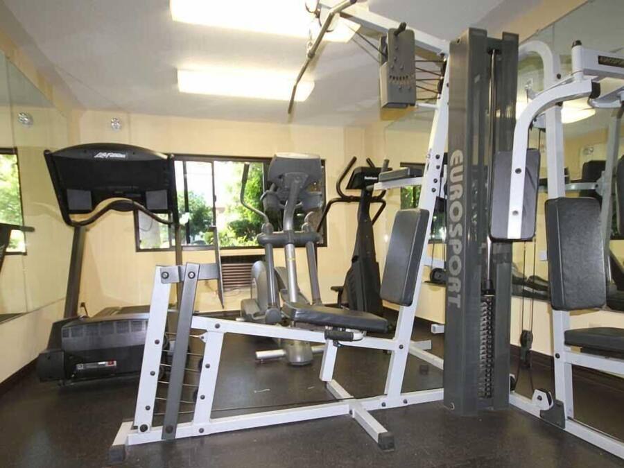 Un gimnasio con equipo de ejercicio, cinta de correr y un espejo.