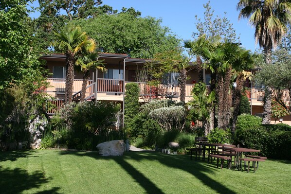 A multi-story hotel with balconies, surrounded by lush greenery and palm trees.
