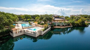 Una località turistica con una piscina centrale, un'area piscine separata e un edificio dal design moderno.
