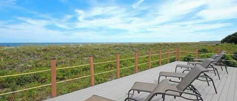 Una terraza con sillones de descanso con vista a la playa.