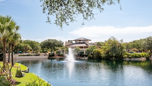 Un hotel con una grande fontana antistante, circondato da una rigogliosa vegetazione e un lago tranquillo.
