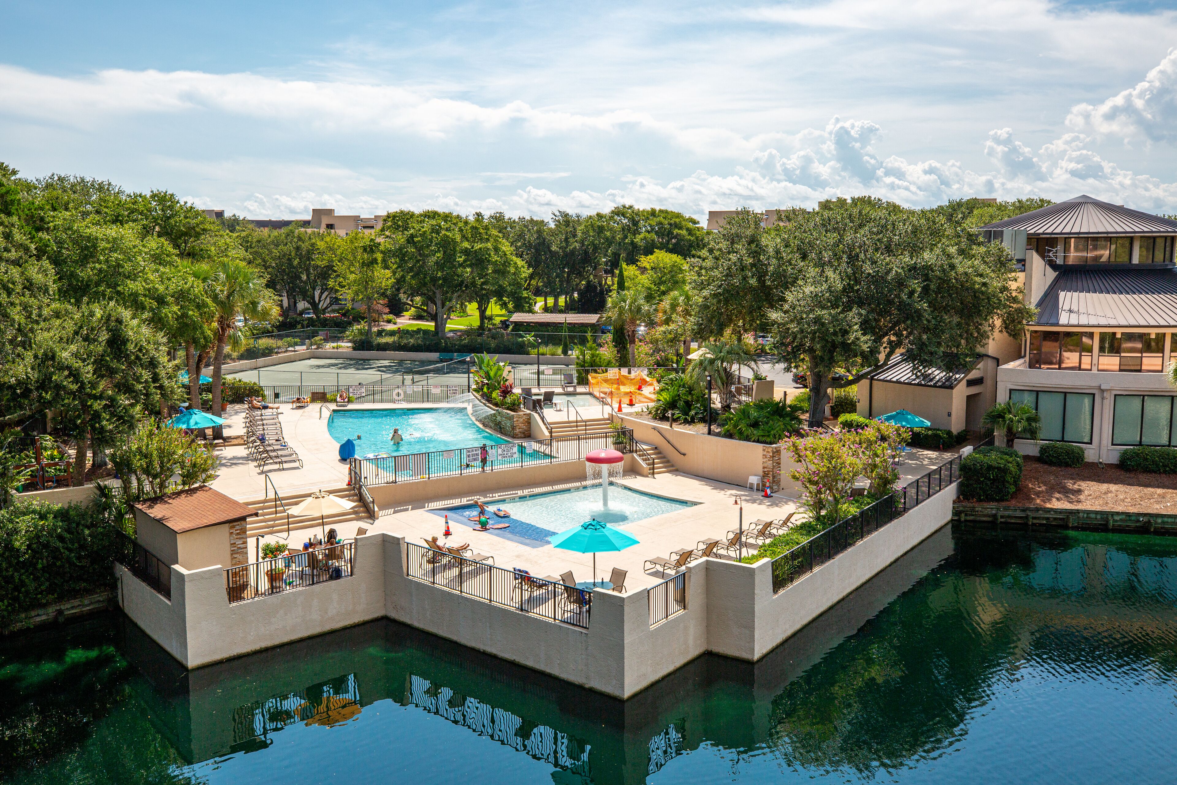 A swimming pool area with multiple pools, sun loungers, and umbrellas.