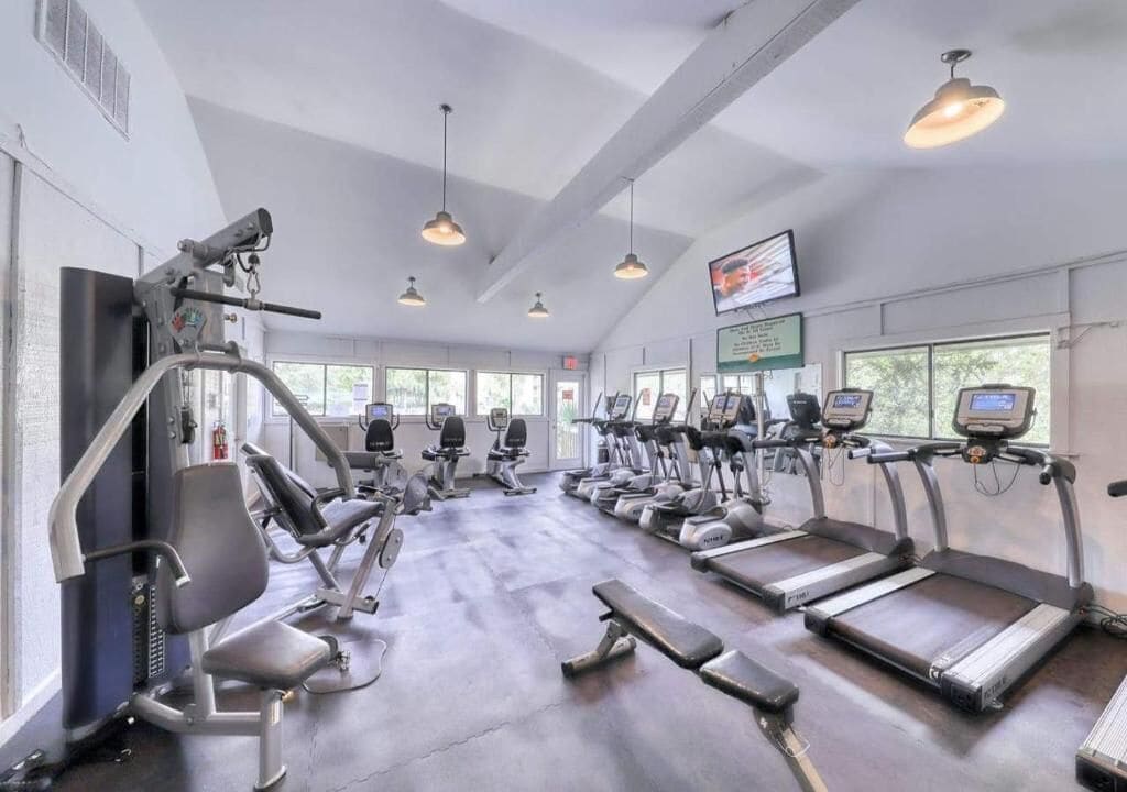A gym with treadmills, elliptical machines, and weight benches.