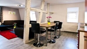Una sala de estar moderna con comedor, que presenta una mesa de madera, sillas negras y un tapete rojo.