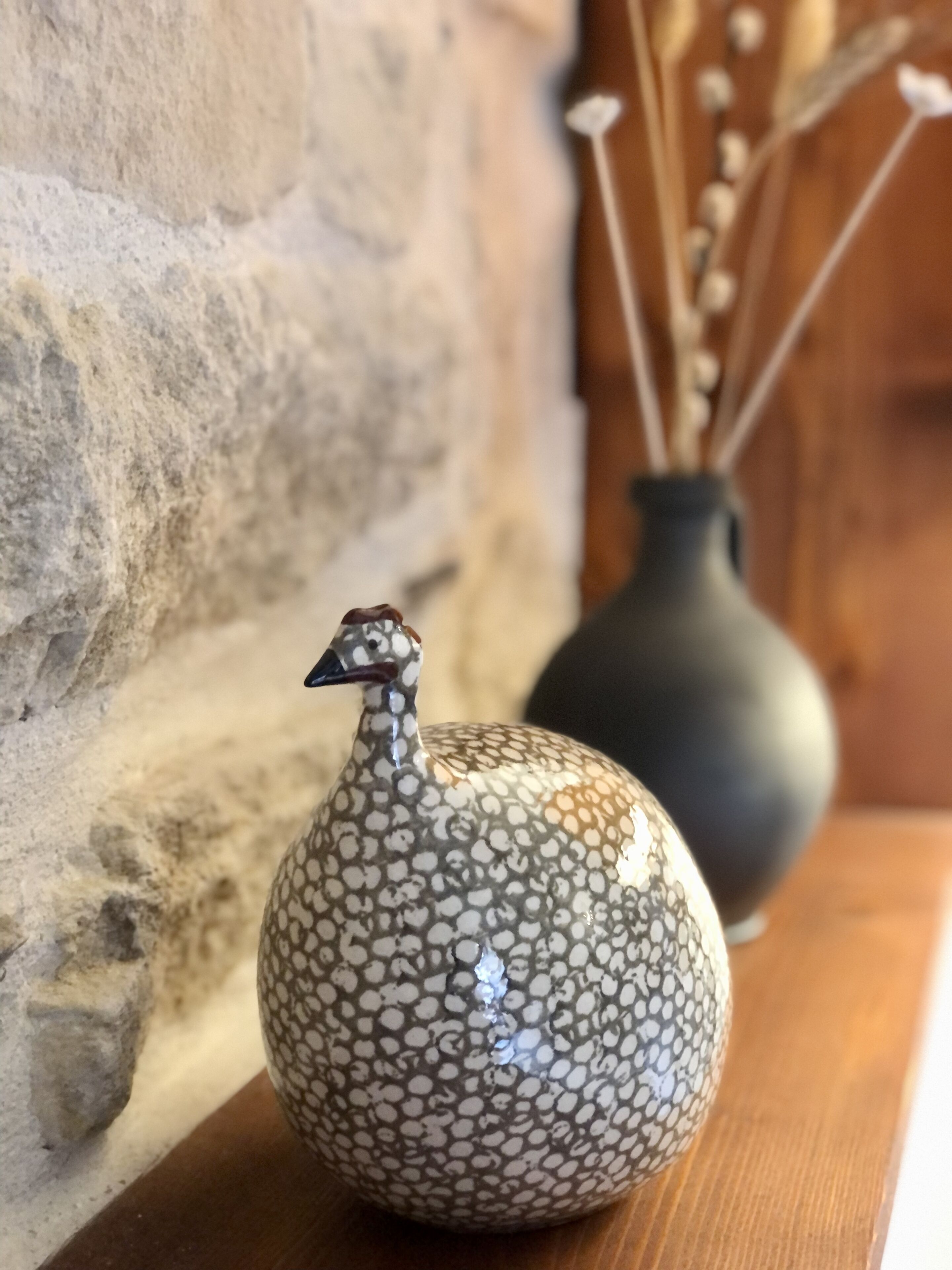 Un vase en céramique en forme d’oiseau, posé sur une surface en bois.