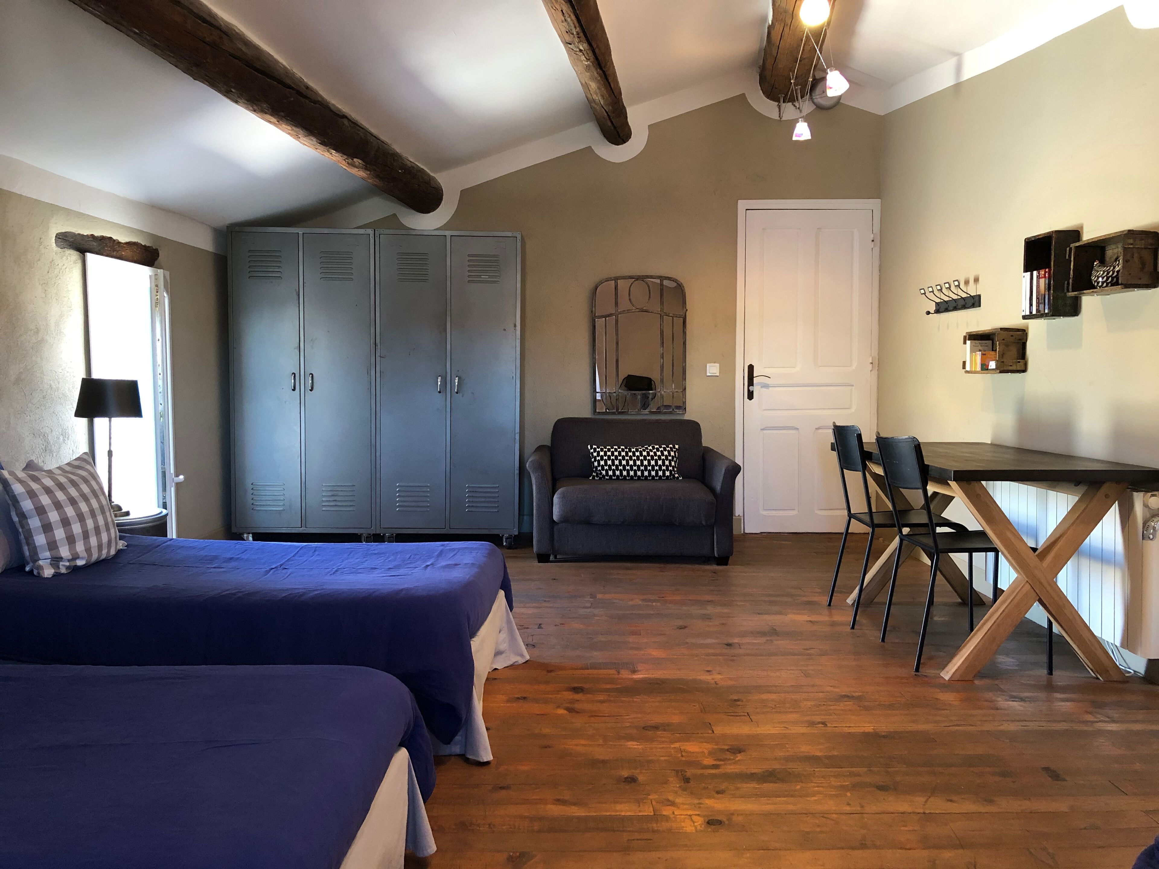 A room with two beds, a desk, a chair, a wardrobe, and a mirror.