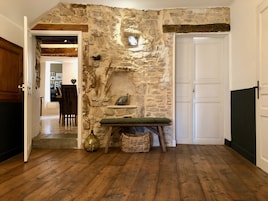 Un interior rústico con pared de piedra, suelo de madera, un banco y una cesta.