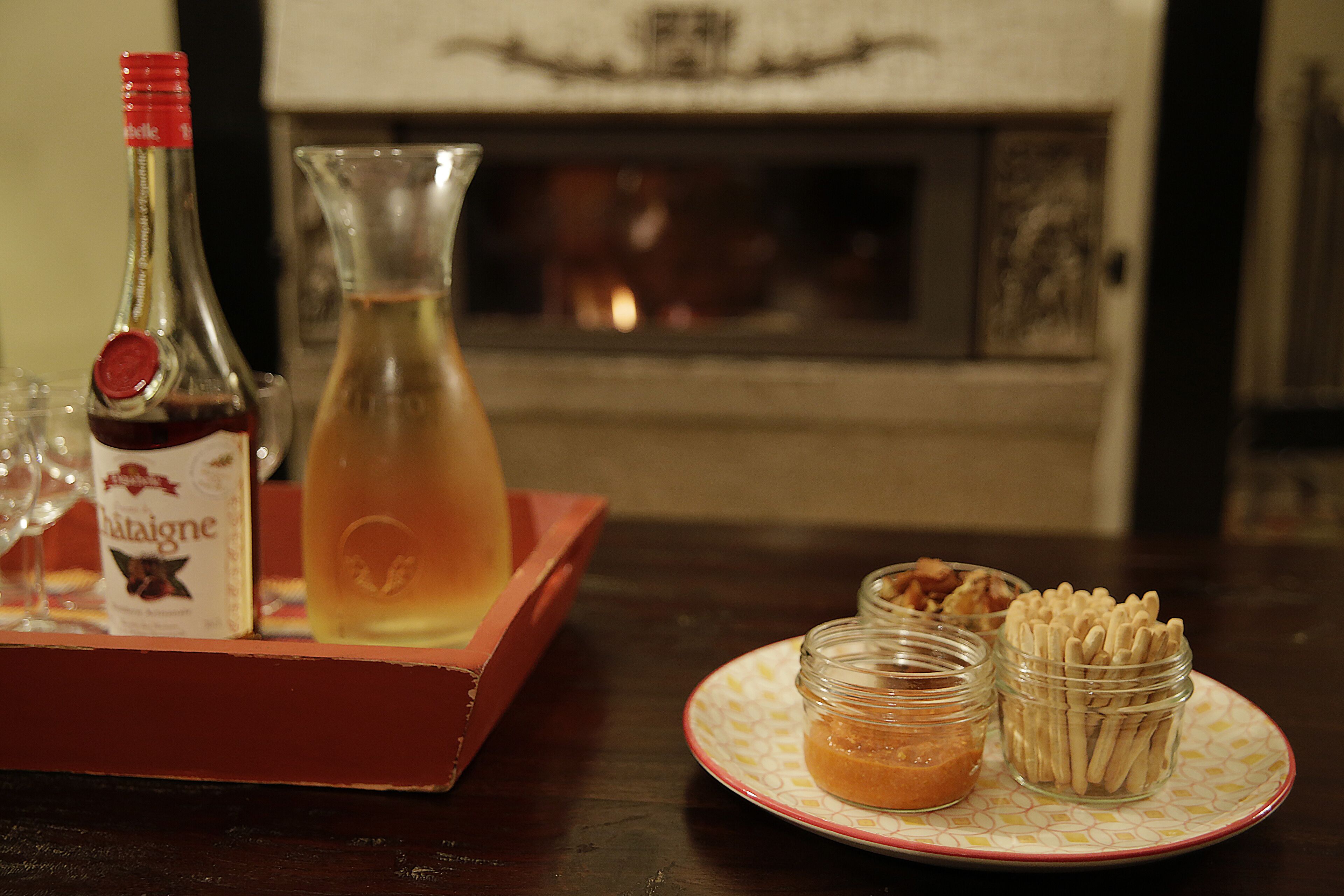 A bottle of Châteaigne wine, a glass pitcher, and two small jars with snacks on a table.