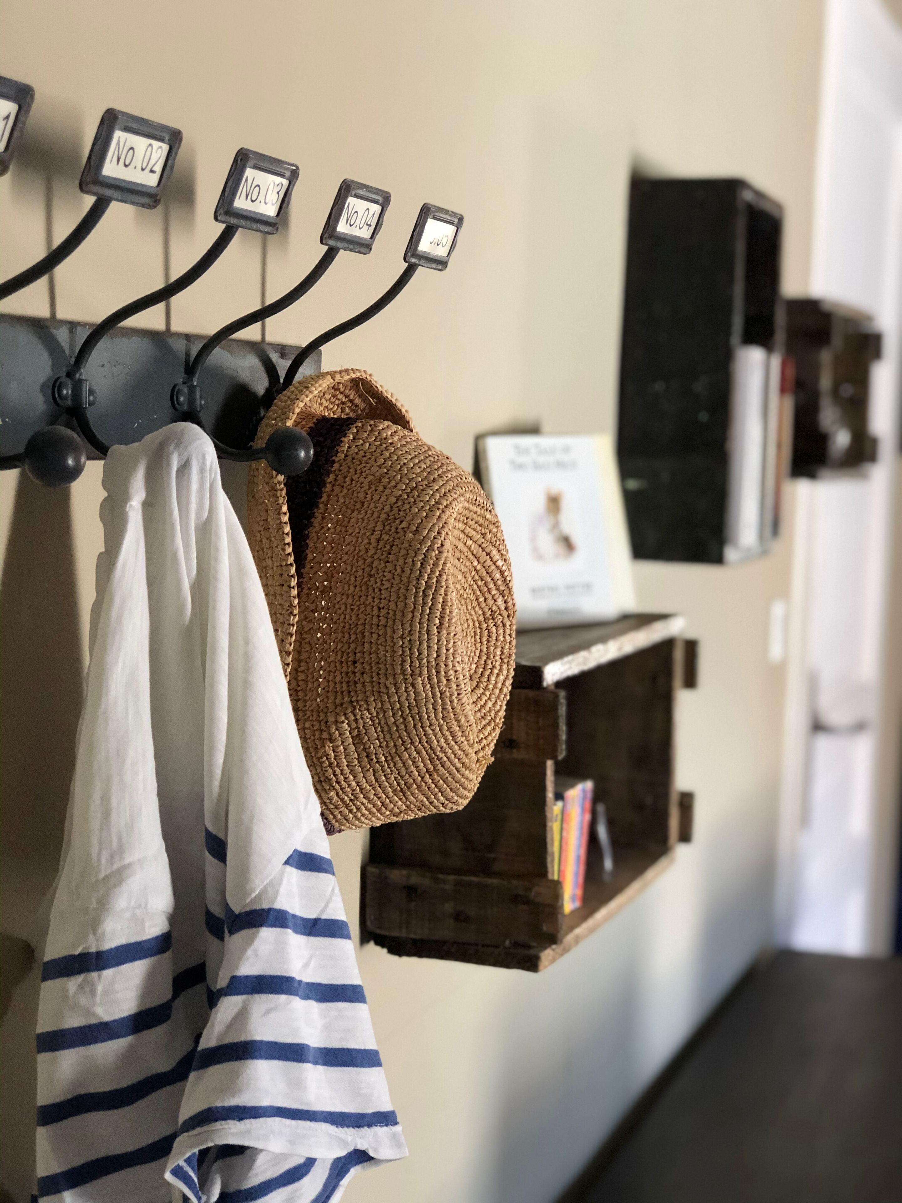 A wall-mounted coat rack with numbered hooks, a woven hat, and striped towels.