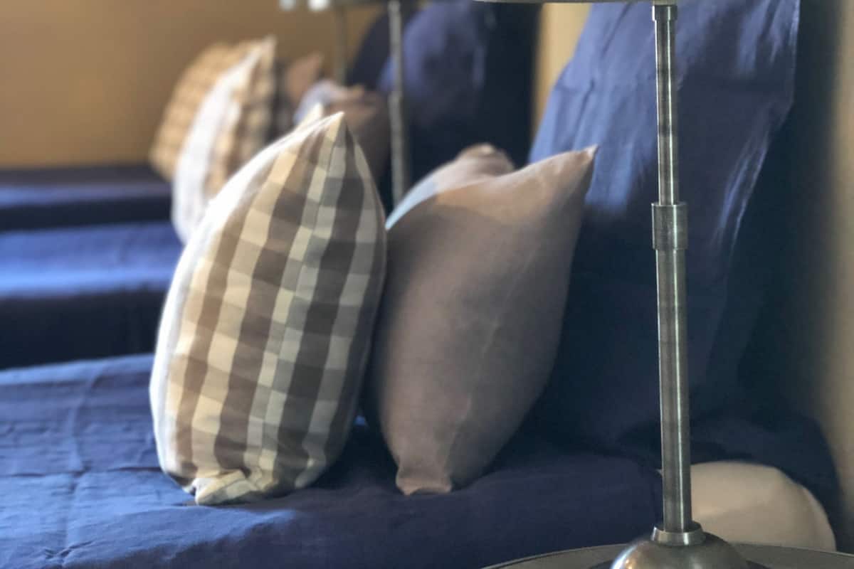 Una habitación con una cama, una lámpara y una estantería fijada a la pared.