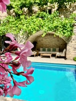 Una zona de piscina con una estructura de piedra y sillas de descanso.