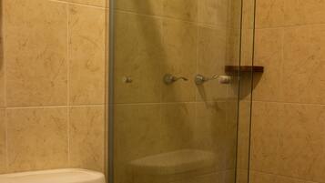 A bathroom with a toilet, a glass shower enclosure, and a towel on the toilet.