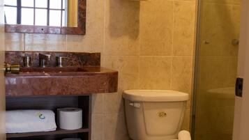 A bathroom with a marble sink, toilet, and a glass shower enclosure.