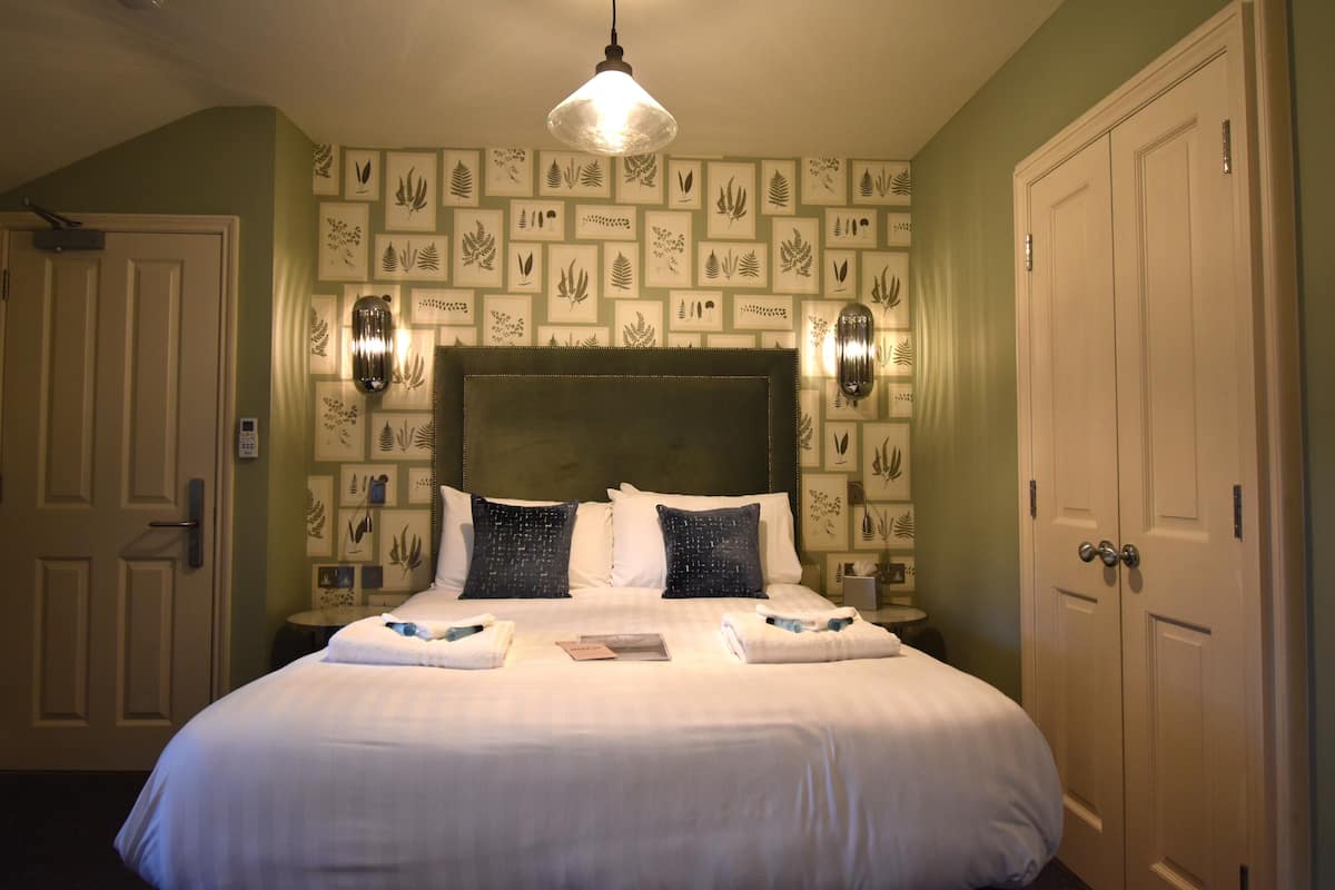 A neatly made bed with white linens, a headboard, and decorative wall art.