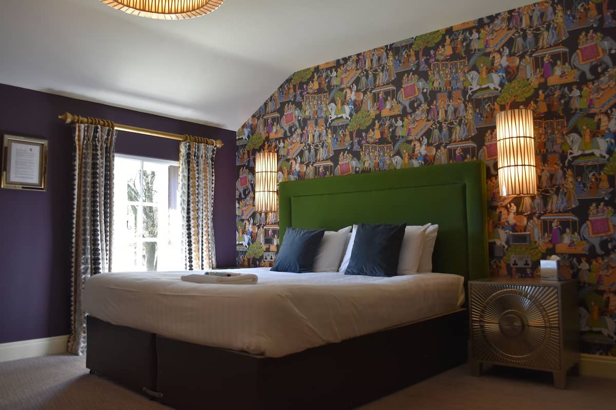 A bedroom with a large bed, purple walls, and a colorful mural.