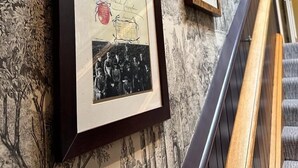 Eine Wand mit gerahmten historischen Fotografien und eine Treppe.