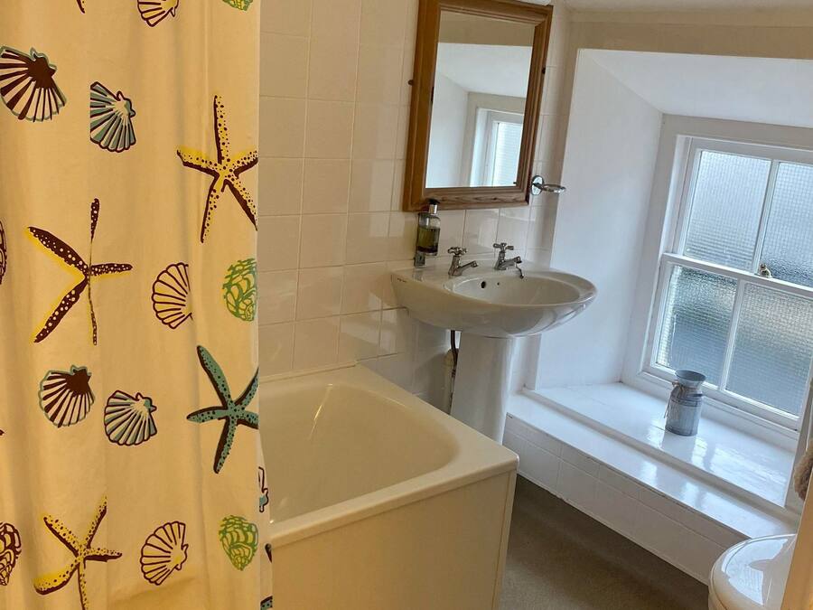 A bathroom with a bathtub, a sink, and a window.