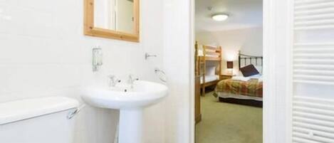 A bathroom with a white sink, mirror, and toilet.