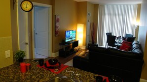 Una sala de estar con televisor, un sofá y un comedor con sillas.