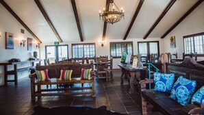 A spacious interior with wooden furniture, a chandelier, and large windows. - Hacienda de Leal,  BW Signature Collection (San Juan Bautista)
