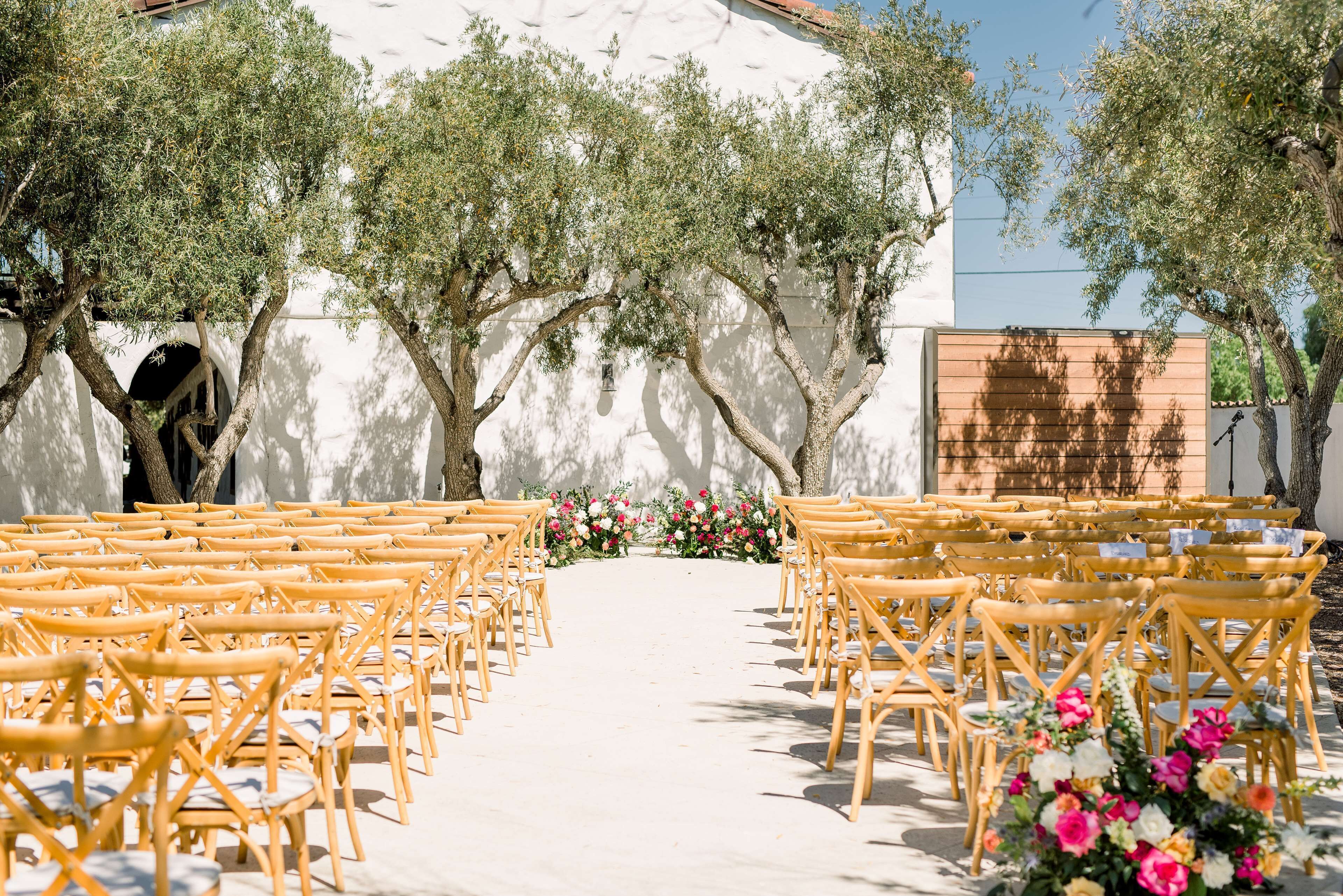 Rows of wooden chairs arranged in a semi-circle with a floral arrangement at the center.