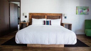 A large bed with white linens, a wooden headboard, two bedside tables with lamps, and a green chair. - Hacienda de Leal,  BW Signature Collection (San Juan Bautista)