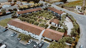 A large building with multiple floors, surrounded by a parking lot and landscaped areas with trees and shrubs. - Hacienda de Leal,  BW Signature Collection (San Juan Bautista)