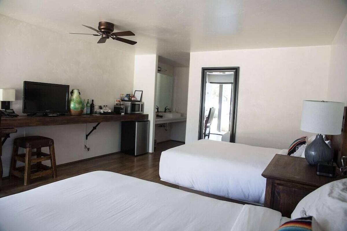 Ein Hotelzimmer mit zwei Betten, einem Schreibtisch, einem Fernseher, einer Mikrowelle und einem Kühlschrank.