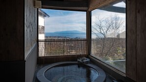 Uma banheira de hidromassagem com vista para montanhas e árvores através de amplas janelas.