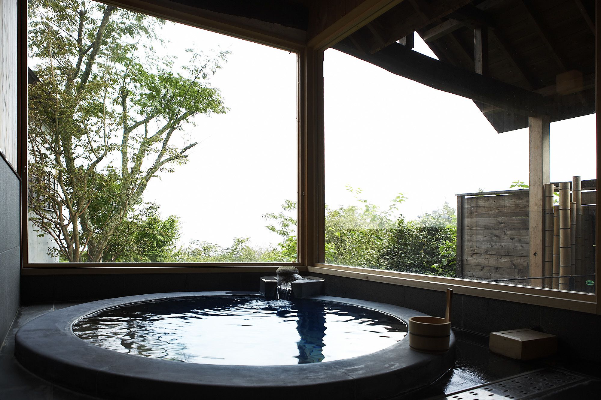 A hot tub with a view of trees through a large window.