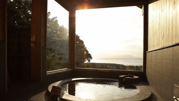 Casa de banho com banheira, vista para o mar e decoração em madeira.