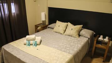 A neatly made bed with a floral bedspread, two pillows, and a set of toiletries on the bedside table.