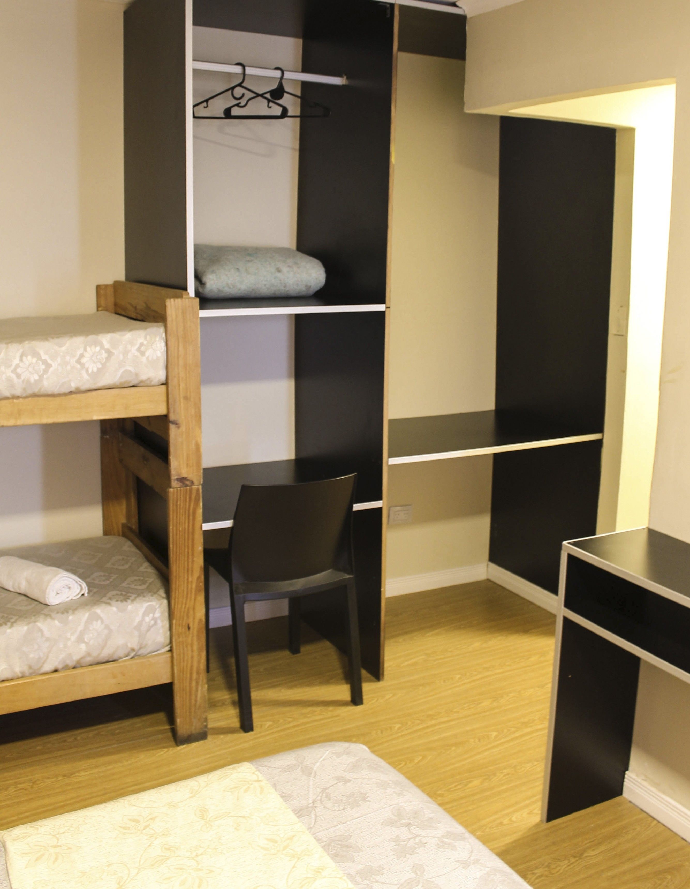 Ein Stockbett mit Schreibtisch und Stuhl, ein kleiner Tisch und ein Kleiderschrank.