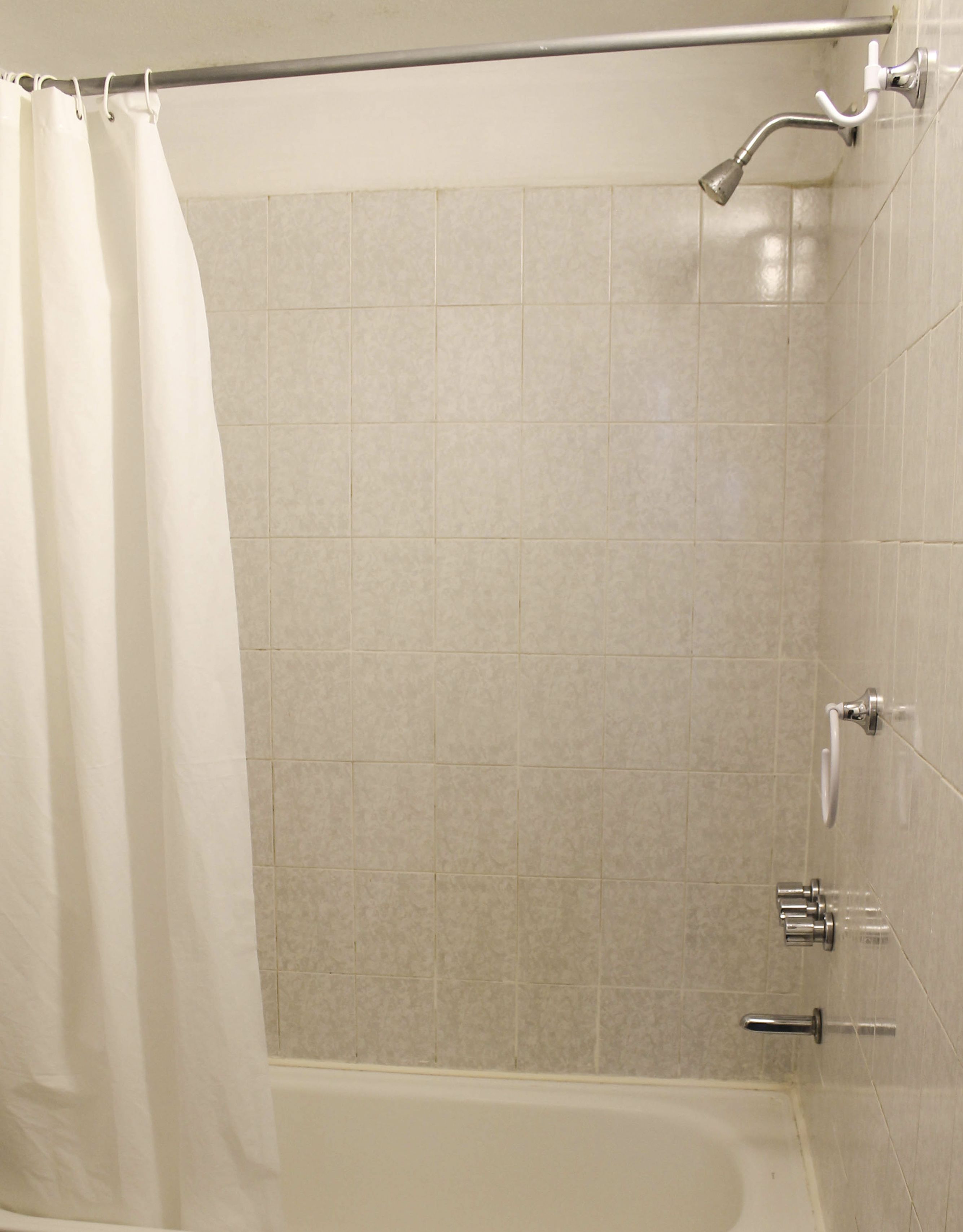 Ein Badezimmer mit einer Badewanne, einer Duschbrause und einem Vorhang.