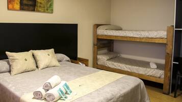 A room with a single bed, two pillows, a rolled-up towel, and a bunk bed.