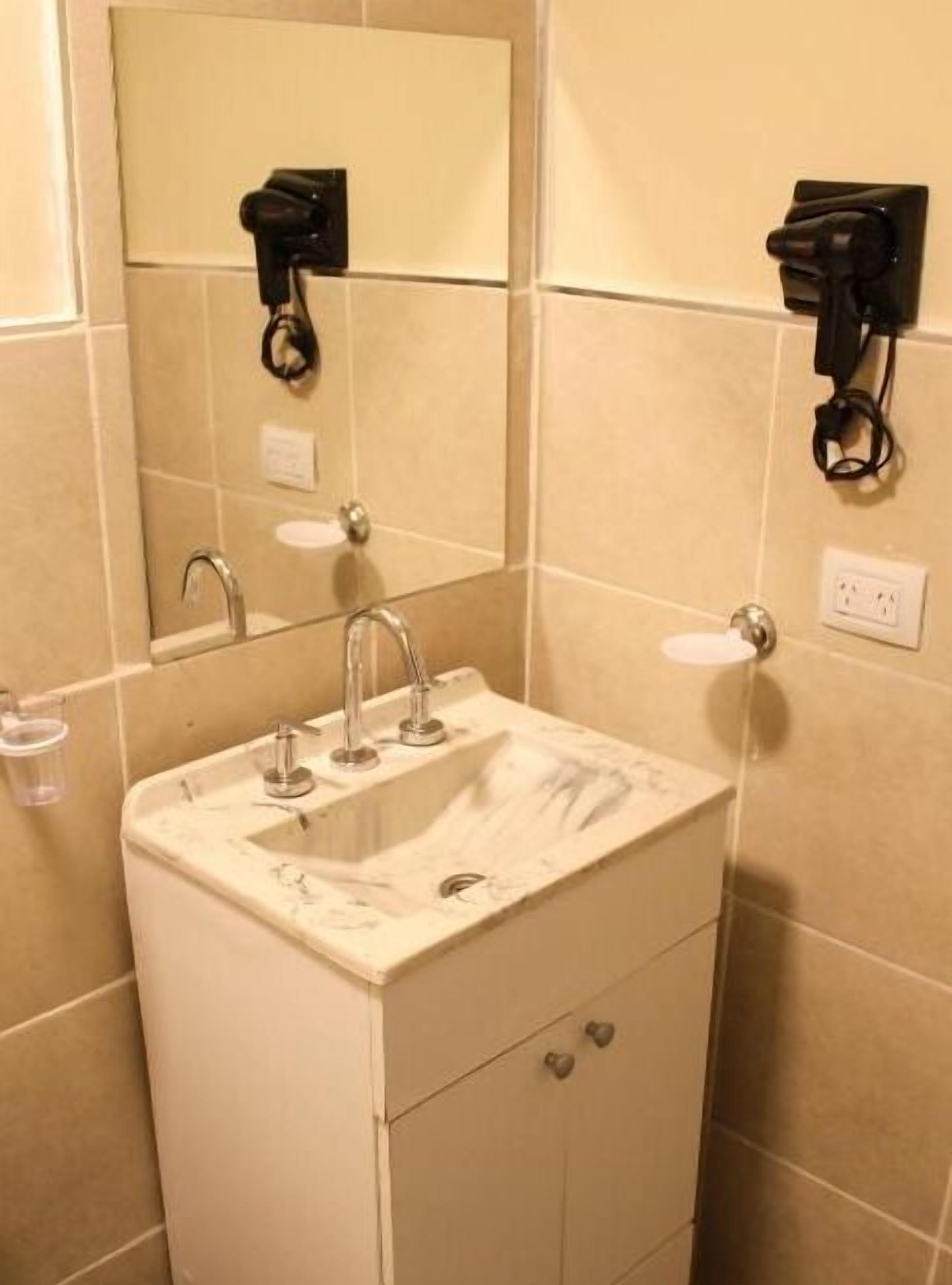 A bathroom with a sink, mirror, and towel rack.