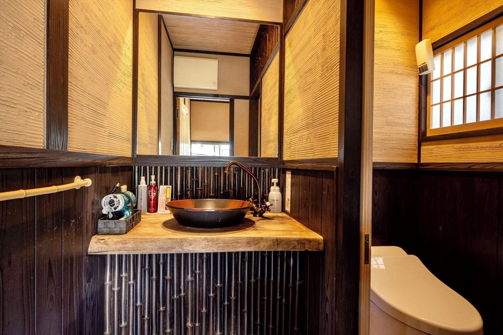 A narrow bathroom with a wooden vanity, a large sink, and a toilet.