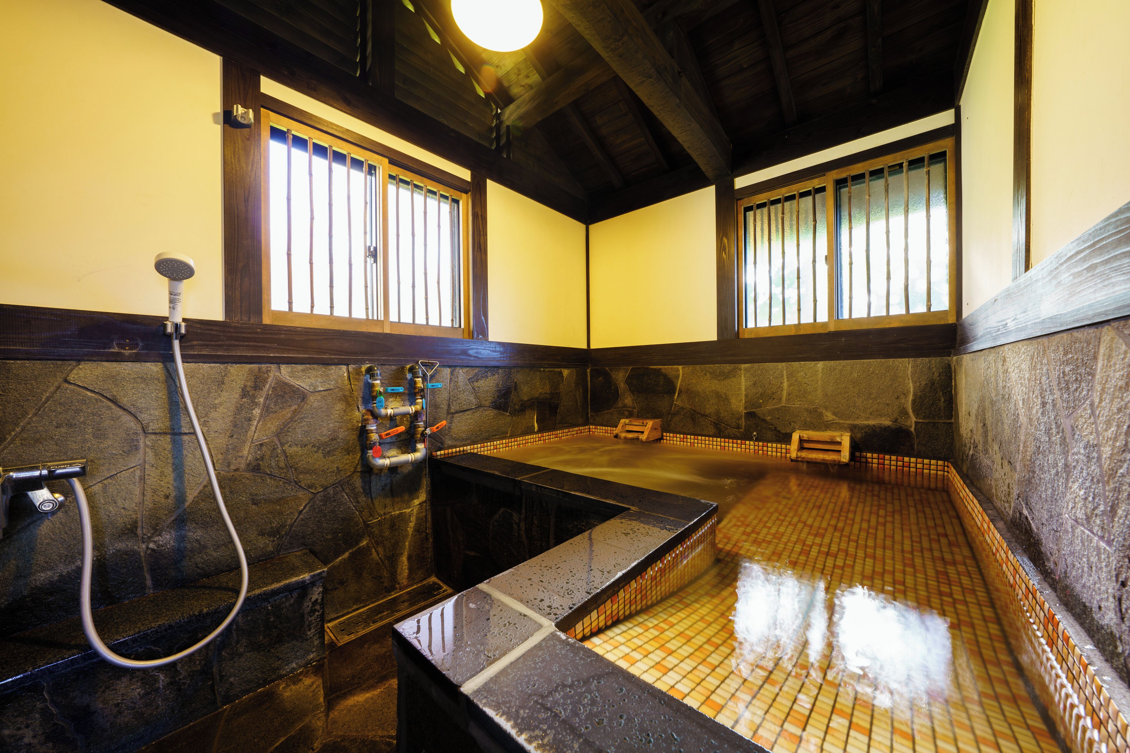 Ein traditionelles japanisches Onsen mit Steingrotte, Holzbalken und Tatami-Böden.