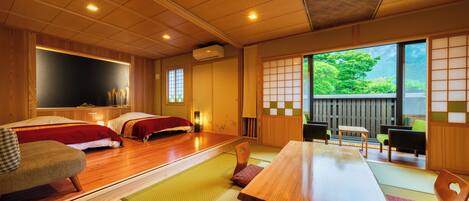 A traditional Japanese room with tatami flooring, a wooden table, and futon beds.